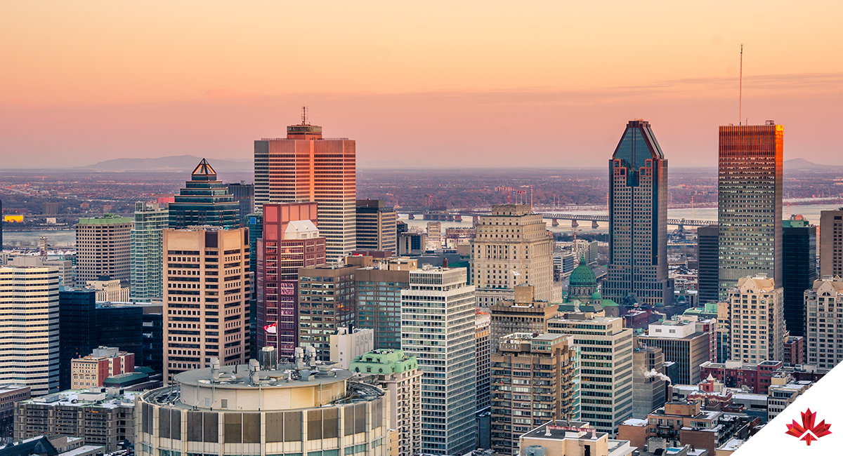 Sunset over Downtown Montréal cityscape with high rise buildings and Saint Lawrence river visible in the background.