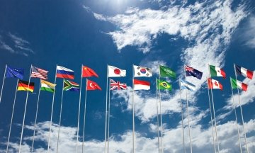 Blue cloudy sky background with the G20 membership countries flags. 