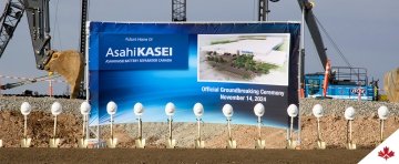  Construction equipment in the background and shovels with helmets in the foreground. A blue sign announced the home of Asahi Kasei's official groundbreaking ceremony on November 14, 2024.