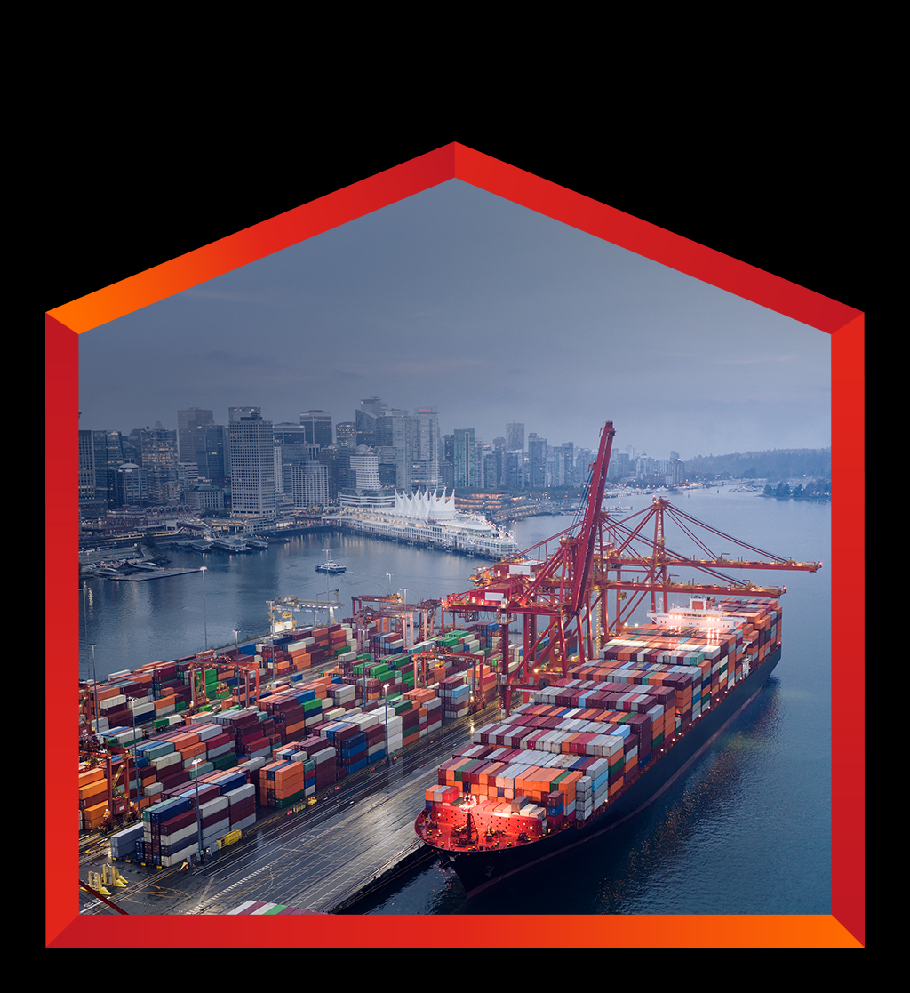 An aerial view shows a massive container ship docked at a port, heavily loaded with thousands of colorful shipping containers. Large red gantry cranes extend over the ship, ready for loading or unloading in Canada.
