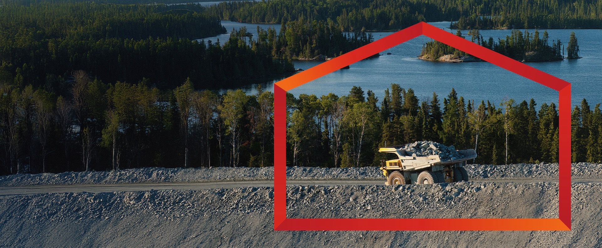 A large, yellow and grey mining dump truck, heavily loaded with rocks, drives on a dirt road in Canada.